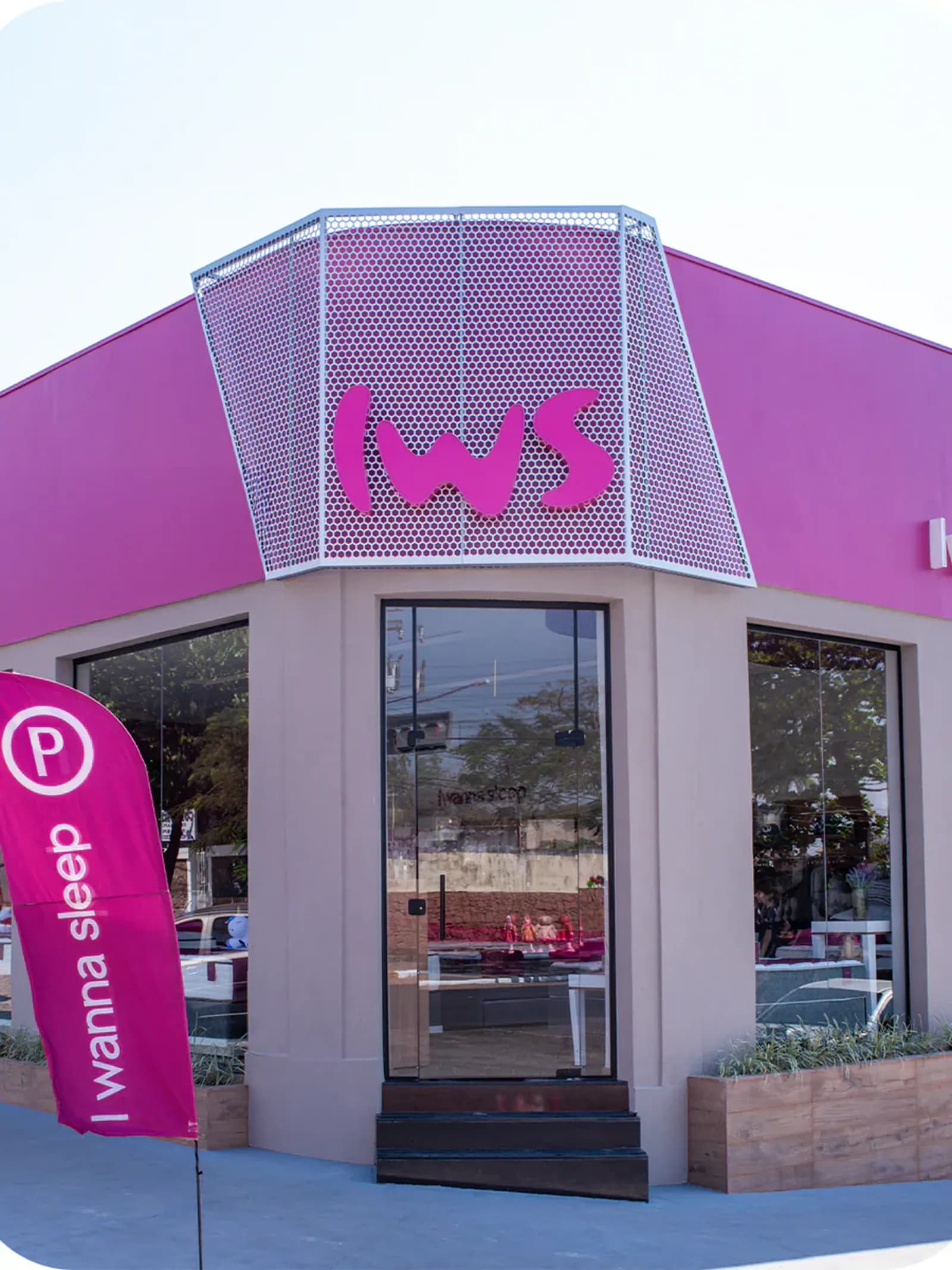Fachada de uma loja física da I Wanna Sleep, com letra 'IWS' em destaque e bandeira da marca