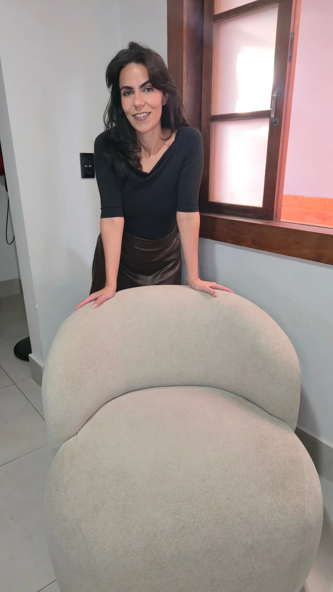 Cecília sentada na Poltrona Moon, destacando o design escultural da peça.