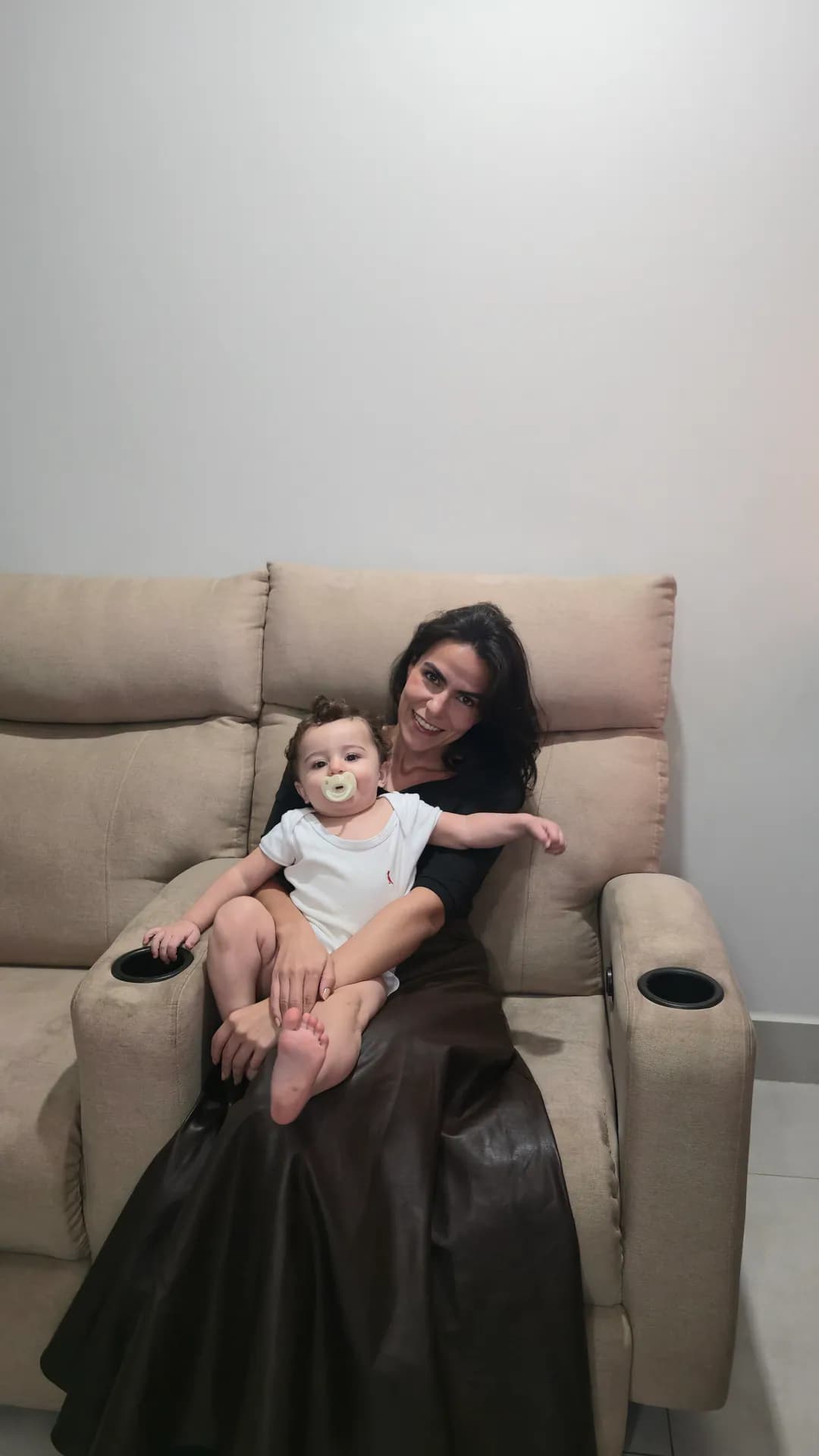 Cecília com o Ian no colo na poltrona reclinável.