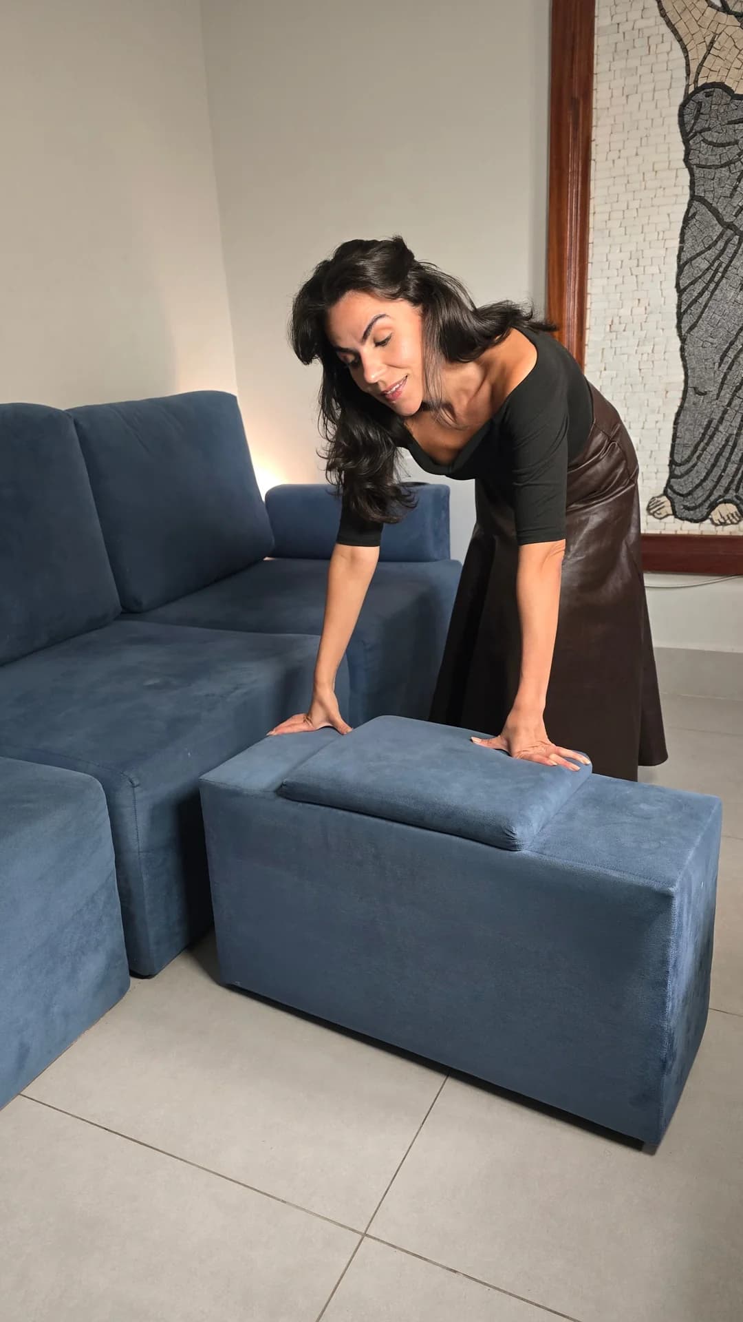 Cecília mostrando a composição modular do sofá Damie na sala.