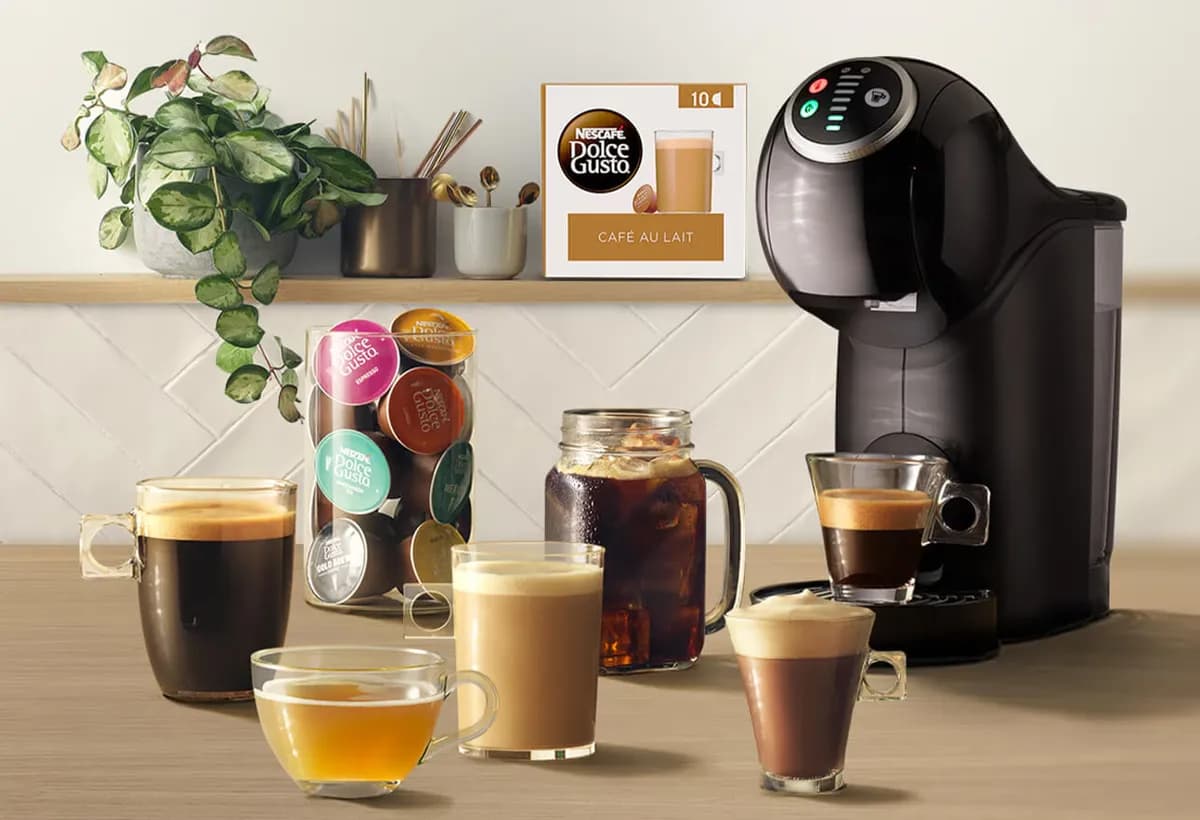 Celular com tela de programa de recompensas ao lado de café e cápsulas em uma mesa clara
